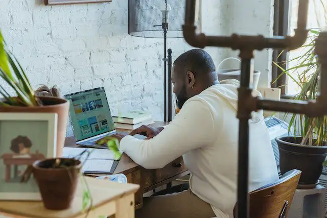 Focused black man typing on laptop during remote work