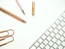 Pens Near Keyboard and Paper Clips