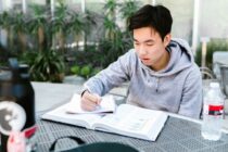 Man in Gray Hoodie Reading a Book