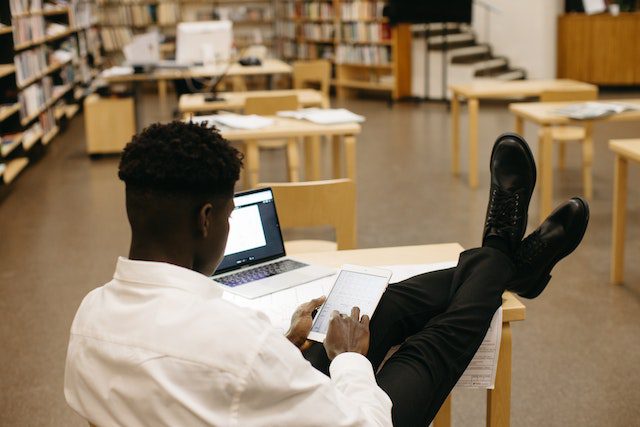 A Man Using Tablet while Sitting with His Feet on Table