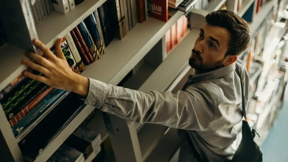 High-Angle Photo of Man Looking for a Book