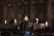 back view of a man wearing an academic dress and square academic cap