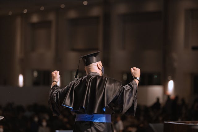 back view of a man wearing an academic dress and square academic cap