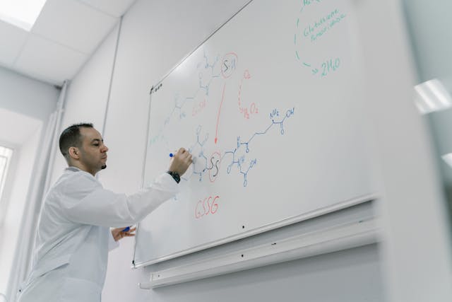 chemistry teacher writing on whiteboard