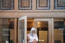 ethnic woman in hijab near building door