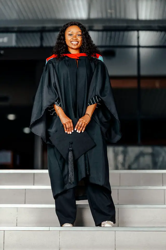 happy graduate standing on steps in cap and gown