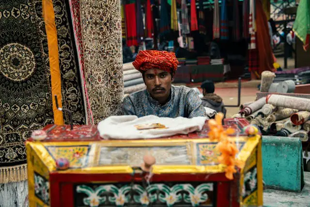 indian bazaar vendor with traditional rugs