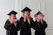 women wearing graduation caps blowing confetti