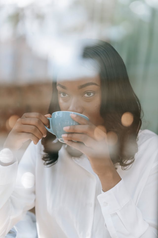 a woman in white long sleeves drinking a coffee