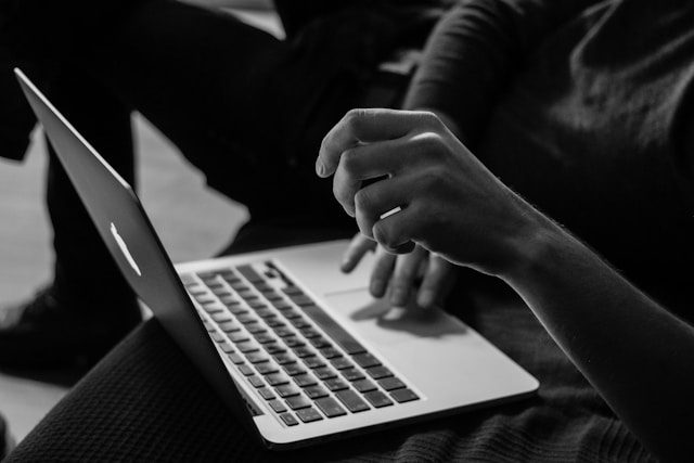 grayscale photo of person using macbook