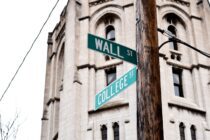 wall street signage on brown wooden post