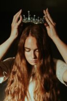 woman putting silver colored tiara on her head