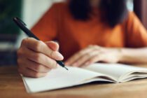 Close up woman hand writing on notebook .