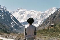 back view of a person looking at the snow covered mountains