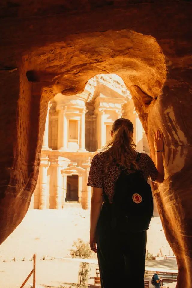 back view of woman with backpack looking at ancient architecture