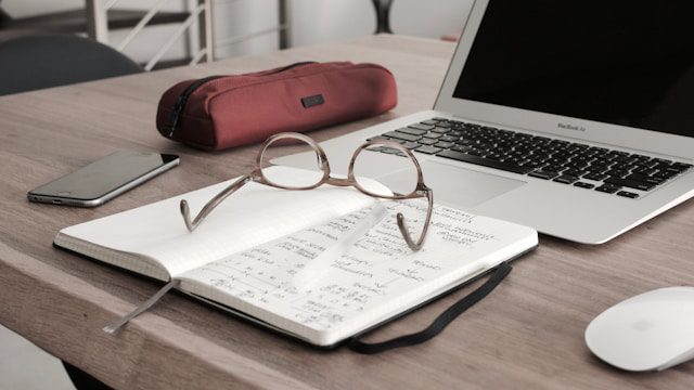 eyeglasses on book beside laptop