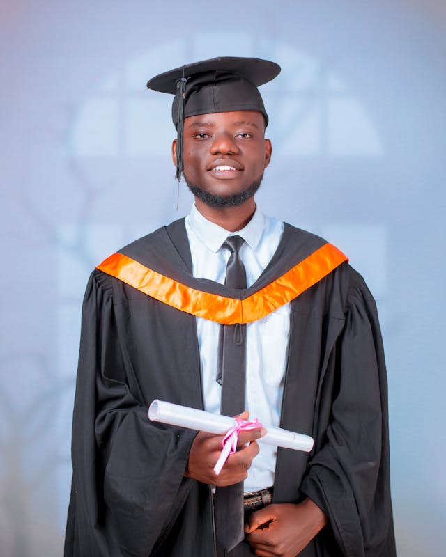 young graduate holding diploma in cap and gown