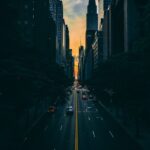 low light photography of vehicle crossing road between high rise buildings