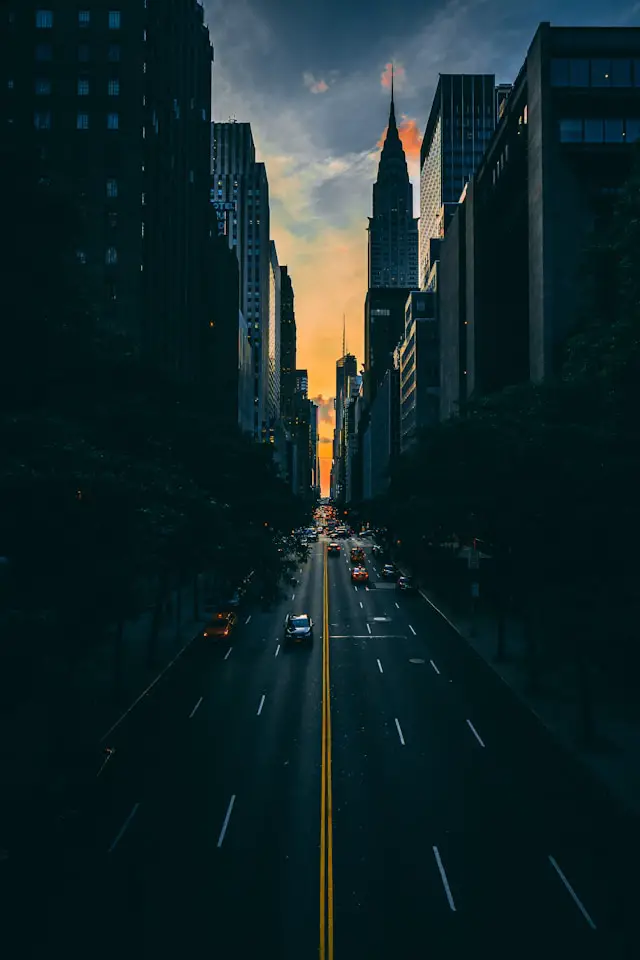 low light photography of vehicle crossing road between high rise buildings