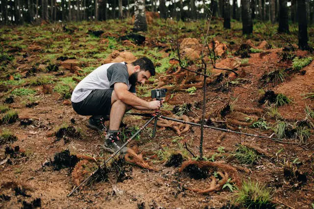 man installing camera on ground in woodland