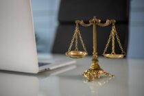 a golden balance scale beside a laptop