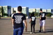 back view photo of a man wearing a black printed t shirt and blue denim jeans