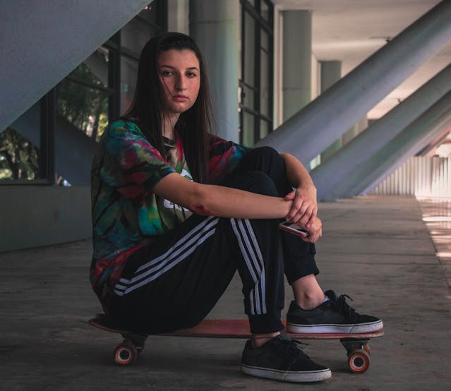 photo of girl sitting on skateboard