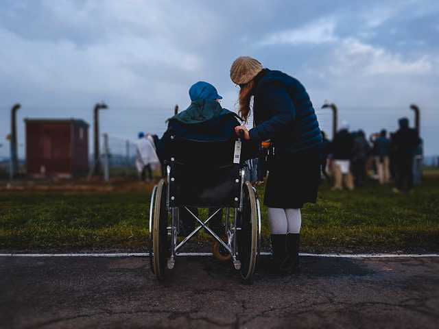 woman standing near person in wheelchair near green grass