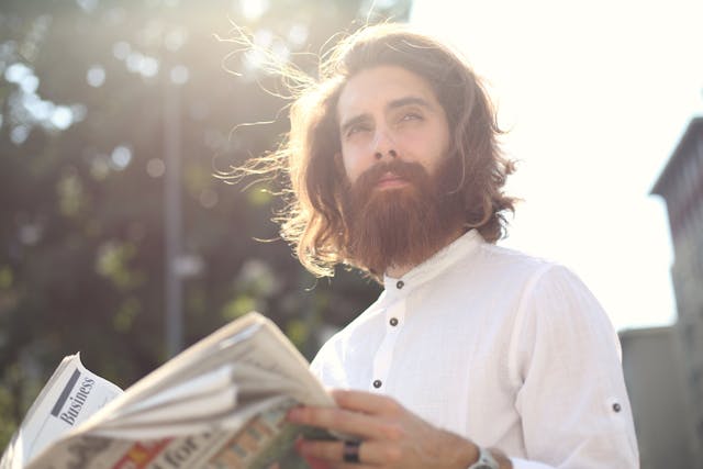 man in white long sleeves reading a newspaper